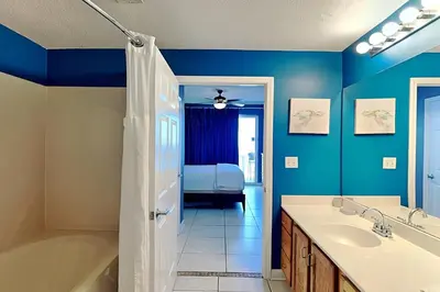 a bathroom with blue walls and a tub and a sink at Sterling Reef #305 in Panama City Beach