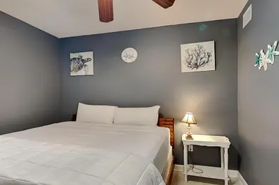 a bedroom with a white bed and a tv at Sterling Reef #305 in Panama City Beach