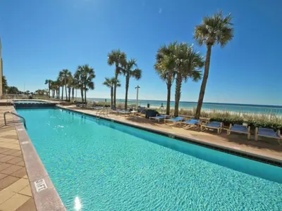 a swimming pool next to the beach with palm trees at Sterling Reef #305 in Panama City Beach
