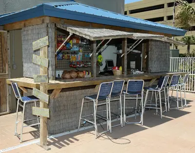 a bar with blue stools in front of a building at Tidewater 1909 in Panama City Beach