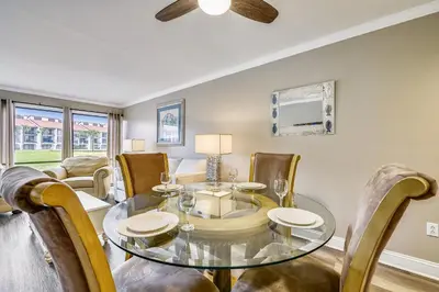 a dining room with a glass table and chairs at Latitude Adjustment by Book That Condo in Panama City Beach