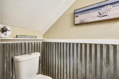 a bathroom with a toilet and a painting on the wall at Gulf Highlands 170 by Book That Condo in Panama City Beach