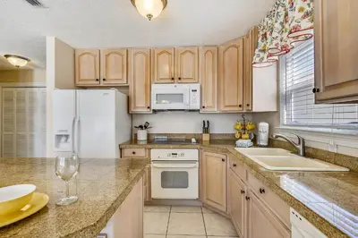 a kitchen with wooden cabinets and white appliances at Beaches and Dreams by Book That Condo in Panama City Beach