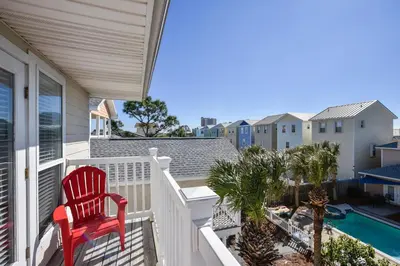 a red chair sitting on the balcony of a house at Beaches and Dreams by Book That Condo in Panama City Beach