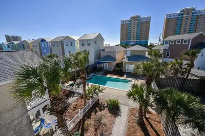 an aerial view of a pool with palm trees and buildings at Beaches and Dreams by Book That Condo in Panama City Beach