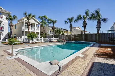 a swimming pool in front of a house with palm trees at Beaches and Dreams by Book That Condo in Panama City Beach