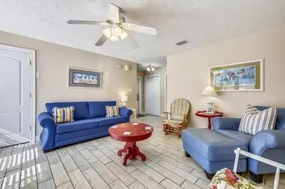 a living room with blue furniture and a ceiling fan at Beaches and Dreams by Book That Condo in Panama City Beach