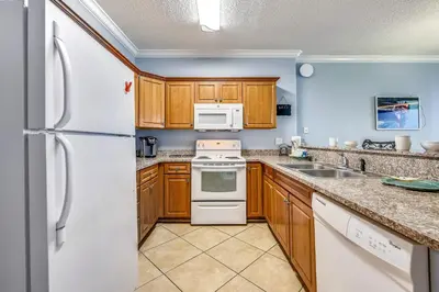 a kitchen with wooden cabinets and white appliances at Twin Palms Resort 1604 by Book That Condo in Panama City Beach
