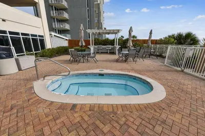 a small pool on a brick patio with tables and chairs at Twin Palms Resort 1604 by Book That Condo in Panama City Beach