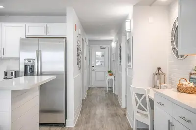 a kitchen with white cabinets and a refrigerator at Modern Beach Vibe with a Breathtaking View - Stunning Pool - Pier Park in Panama City Beach