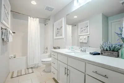 a white bathroom with a sink and a toilet at Modern Beach Vibe with a Breathtaking View - Stunning Pool - Pier Park in Panama City Beach