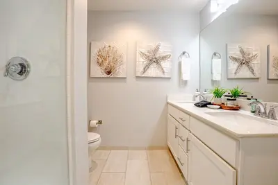 a bathroom with a toilet and two paintings on the wall at Modern Beach Vibe with a Breathtaking View - Stunning Pool - Pier Park in Panama City Beach