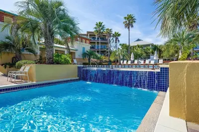 a swimming pool with palm trees and a building at Aquanut Beach House 30A in Inlet Beach