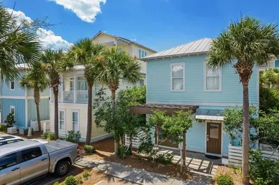 a blue house with palm trees in a street at Aquanut Beach House 30A in Inlet Beach