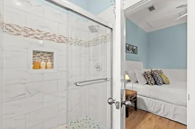 a bathroom with a walk in shower next to a bed at Aquanut Beach House 30A in Inlet Beach