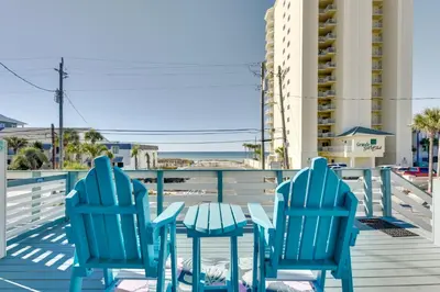 two blue chairs and a table on a deck at PCB Apt with Balcony and Gulf Views Walk to Beach in Panama City Beach
