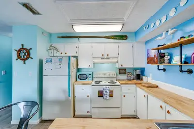 a kitchen with white appliances and blue walls at PCB Apt with Balcony and Gulf Views Walk to Beach in Panama City Beach