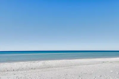 a sandy beach with the ocean in the background at PCB Apt with Balcony and Gulf Views Walk to Beach in Panama City Beach