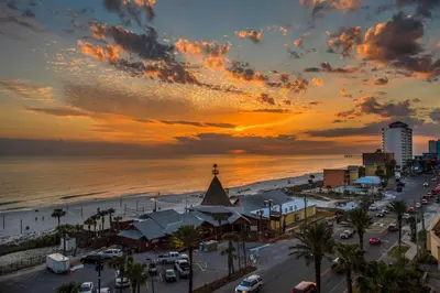 a sunset over the beach and a city with cars at Scenic PCB Condo with Stunning Sunsets and Beach View! in Panama City Beach