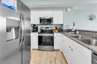 a kitchen with white cabinets and a stainless steel refrigerator at Shores of Panama 830 in Panama City Beach