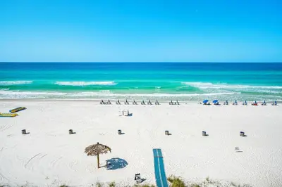 a sandy beach with an umbrella and the ocean at Grandview East 404 in Panama City Beach