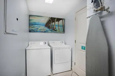 a laundry room with a washing machine and a painting at Grandview East 404 in Panama City Beach