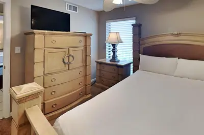 a bedroom with a bed and a dresser with a television at Edgewater Tower II #205 in Panama City Beach