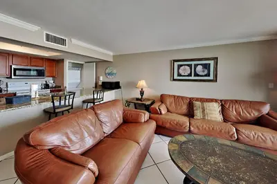 a living room with brown leather furniture and a kitchen at Edgewater Tower II #205 in Panama City Beach