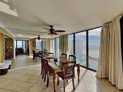 a dining room with a table and chairs and windows at Edgewater Tower I 912 in Panama City Beach