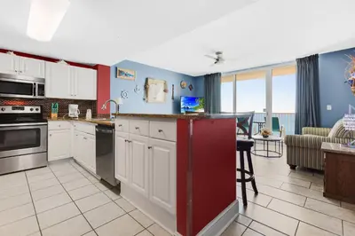 a kitchen with white cabinets and a living room at Majestic Beach Towers I #2210 in Panama City Beach