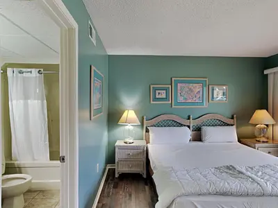 a blue bedroom with a bed and a bathroom at Edgewater Villa #2605 in Panama City Beach