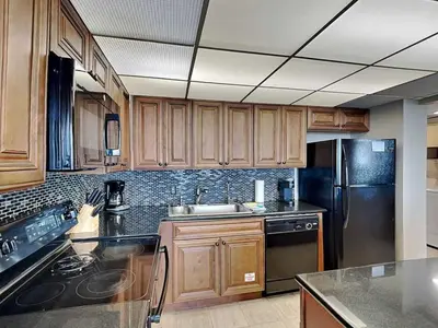 a kitchen with wooden cabinets and a black appliances at Edgewater Tower 1 Unit 101 in Panama City Beach