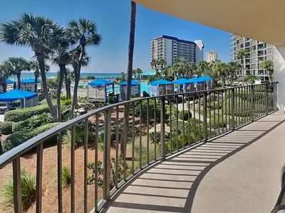 a walkway at the beach with palm trees and blue umbrellas at Edgewater Tower 1 Unit 101 in Panama City Beach