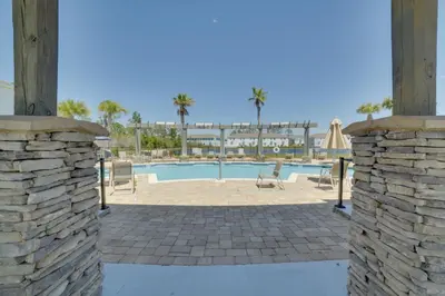 a pool with two chairs and a stone wall at Beautiful PCB Getaway Less Than 3 Mi to the Beach! in Panama City Beach