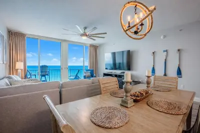 a dining room with a couch and a table with chairs at Totally Beach'n at 1605 Aqua in Panama City Beach