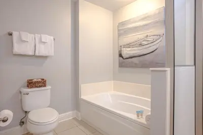 a white bathroom with a toilet and a bath tub at Totally Beach'n at 1605 Aqua in Panama City Beach