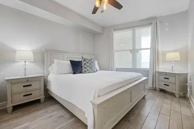 a white bedroom with a bed and two night stands at Totally Beach'n at 1605 Aqua in Panama City Beach
