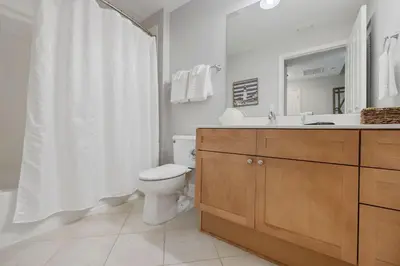 a bathroom with a toilet and a sink and a mirror at Totally Beach'n at 1605 Aqua in Panama City Beach