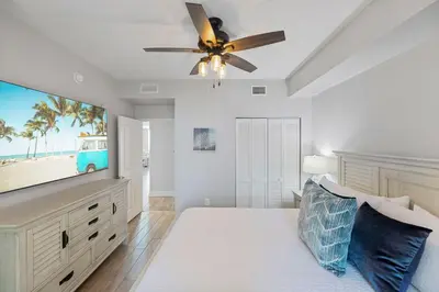 a bedroom with a flat screen tv and a ceiling fan at Totally Beach'n at 1605 Aqua in Panama City Beach