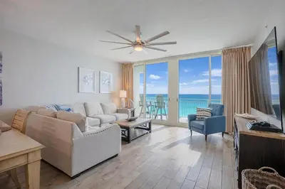 a living room with a couch and a television with a view of the ocean at Totally Beach'n at 1605 Aqua in Panama City Beach