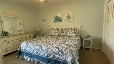a bedroom with a bed and a dresser and a mirror at Desirable Pet Friendly Resort, 3 minute walk to the Beach, Beachside Pool & Restaurant Message for Snow Bird Rates in Panama City Beach