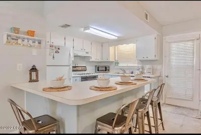 a kitchen with white cabinets and a counter with chairs at Desirable Pet Friendly Resort, 3 minute walk to the Beach, Beachside Pool & Restaurant Message for Snow Bird Rates in Panama City Beach