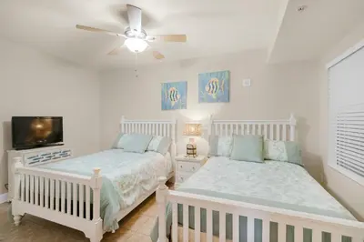 a bedroom with two beds and a flat screen tv at Tidewater 302 in Panama City Beach