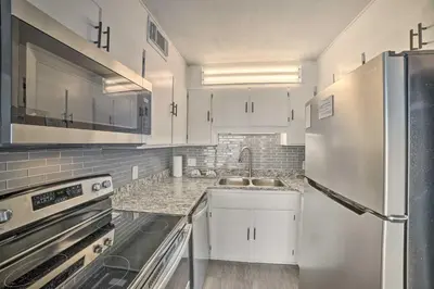 a kitchen with white cabinets and a stainless steel refrigerator at Oceanfront Panama City Beach Condo with Pool Access in Panama City Beach