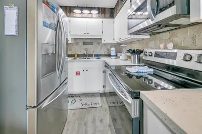 a kitchen with white cabinets and a stainless steel refrigerator at The Summit 924 in Panama City Beach