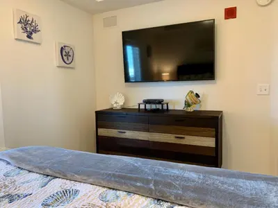 a bedroom with a dresser with a television on the wall at Sunset Cove at Calypso III in Panama City Beach