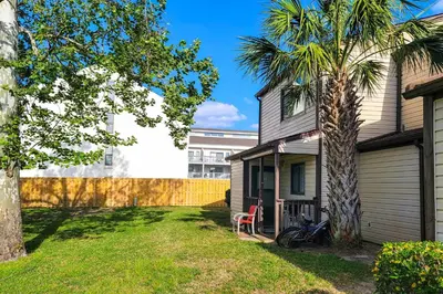 a house with a palm tree in the yard at Beautiful PCB Townhome Balcony and Resort Amenities in Panama City Beach