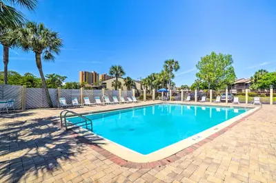 a swimming pool with chairs and palm trees at Beautiful PCB Townhome Balcony and Resort Amenities in Panama City Beach