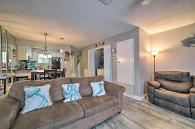 a living room with a brown couch and a kitchen at Beautiful PCB Townhome Balcony and Resort Amenities in Panama City Beach