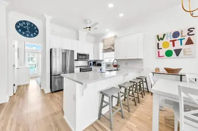 a kitchen with white cabinets and a large island with bar stools at Beach Love in Santa Rosa Beach